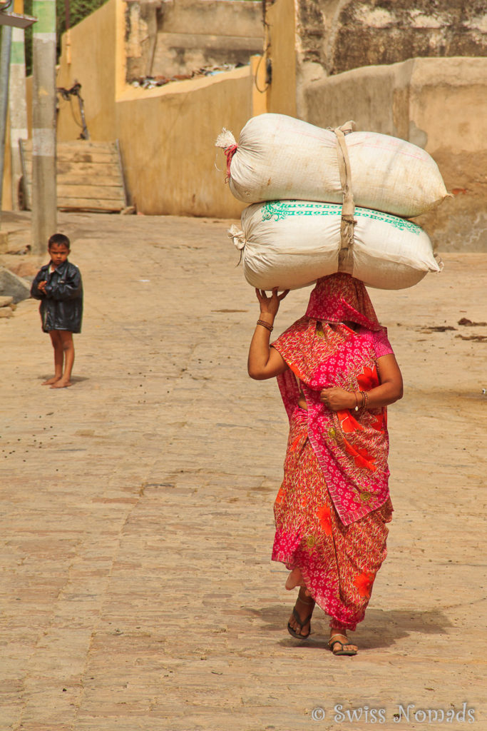 Indische Frau mit eine schweren Last auf dem Kopf in Mandawa